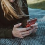 woman in black long sleeve shirt holding red smartphone