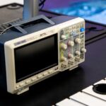 Tektronix DPO718AX : un oscilloscope qui ressemble à un PC A digital oscilloscope on a laboratory workbench, showcasing modern electronic equipment.