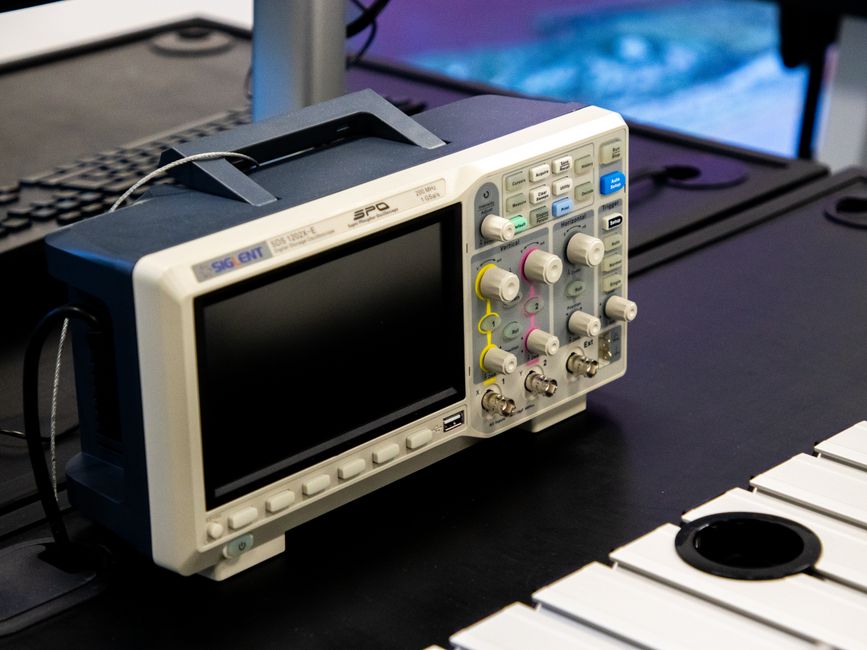 A digital oscilloscope on a laboratory workbench, showcasing modern electronic equipment.