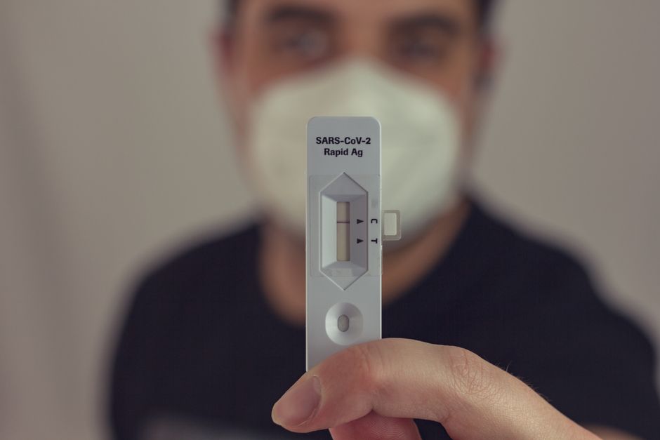 A person holding a negative COVID-19 antigen test with a face mask on, focused on the test result.