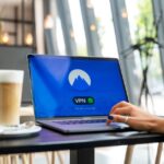 Piratage en ligne : deux projets américains traitent les VPN différemment A person using a laptop with a VPN connection in a modern cafe setting, showcasing remote work and internet security.