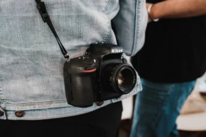 A professional camera hangs on a denim-clad person, showcasing photography essentials.
