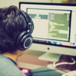 Tokenmaxxing : pourquoi les tokens ne mesurent pas la productivité A programmer with headphones focuses on coding at a computer setup with dual monitors.