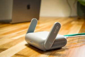 A sleek WiFi 6 router with antennas and cable on a wooden desk, perfect for modern home networks.