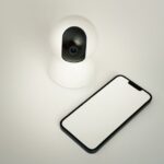 Caméras Tapo vulnérables : modèles concernés et correctifs A smart home security camera paired with a blank smartphone on a white background.