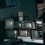 Offres TV Best Buy : quels modèles selon la pièce? A stack of vintage CRT televisions in a dimly lit modern room with abstract art.