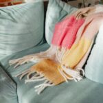 A warm colorful blanket draped on a teal sofa, adding cozy charm to a living room interior.