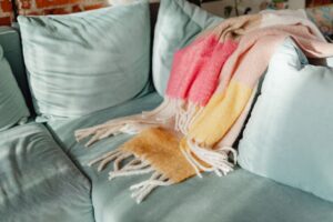 A warm colorful blanket draped on a teal sofa, adding cozy charm to a living room interior.