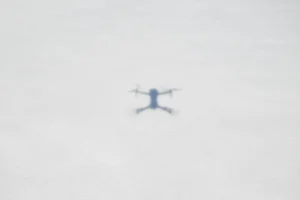 Blurred drone shadow on a snowy ground, illustrating aerial photography.