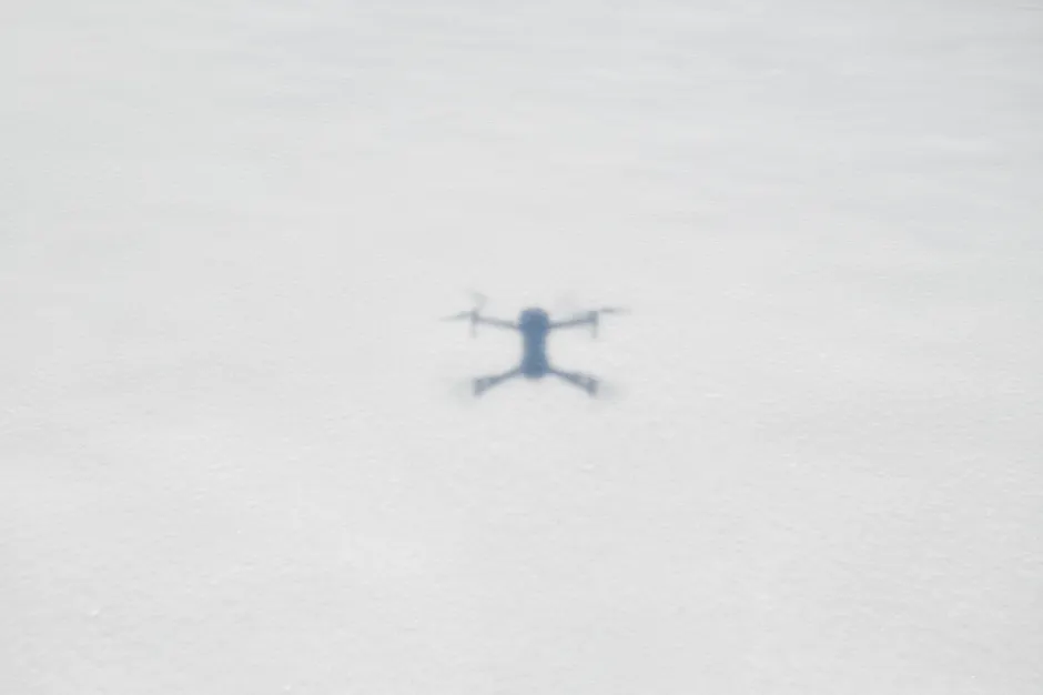 Blurred drone shadow on a snowy ground, illustrating aerial photography.