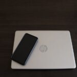 Le Let's Note SC7 mise sur 919 g et une connectique complète Close-up of a smartphone resting on an HP laptop, symbolizing modern technology integration.