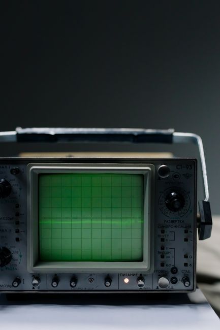 Close-up of a vintage oscilloscope showing a green waveform on a grid screen.