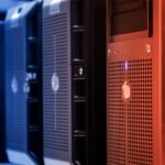 Alerte Kiteworks : pourquoi des clients ont arrêté leurs serveurs Close-up of tower servers in a data center with blue and red lighting.