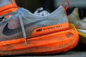 Close-up of worn Nike Invincible Run 3 shoes on concrete, showing wear and tear.