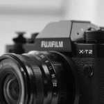 Quels objectifs Fujifilm X choisir selon votre usage? Detailed black and white image focusing on a Fujifilm X-T2 camera and lens.