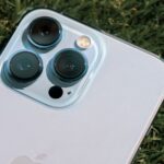 Vivo X500 Pro Max : zoom 400 mm et vidéo 8K annoncés Detailed close-up of smartphone camera lenses on green grass background.