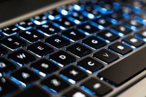 Detailed view of a backlit laptop keyboard keys with blue LED lighting for tech concepts.