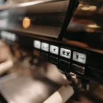 Philips Baristina à 359 dollars australiens : les limites à vérifier Detailed view of espresso machine panel in a cafe setting, highlighting coffee brewing controls.
