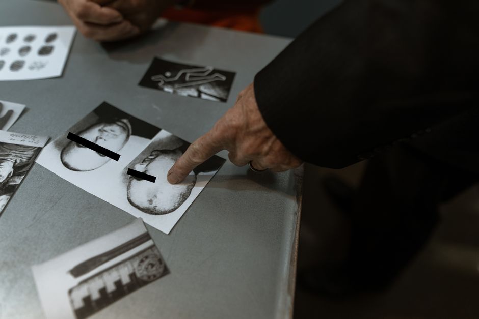 Detective reviewing crime scene photos and fingerprints indoors.