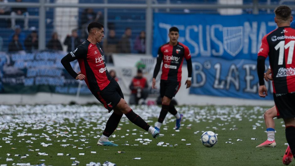 Dynamic scene of soccer players in action during a match with vibrant supporters in the background.