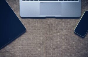 Flat lay of laptop, tablet, and smartphone on burlap surface, promoting technology and connectivity.