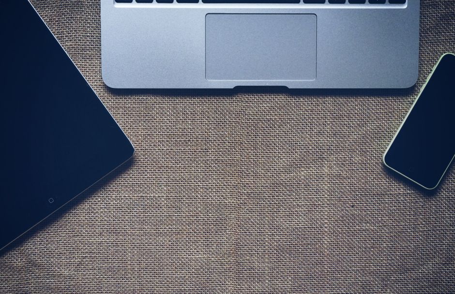 Flat lay of laptop, tablet, and smartphone on burlap surface, promoting technology and connectivity.