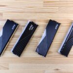 Prix RAM DDR5 : ce qui compte avant l'achat Four XPG DDR5 RAM modules aligned on a wooden surface, showcasing modern computing technology.