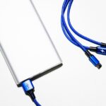 Batterie externe Iniu 20 000 mAh : le câble intégré en pratique Minimalist image of a power bank with blue USB charging cables on a white background.