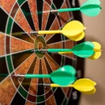 World Grand Prix de fléchettes 2026 : dates, format et diffusion Multiple green and yellow darts precisely hitting a dartboard bullseye, indoor sport scene.