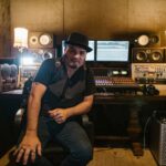 Neal Morse et The Grand Experiment: le pari du studio Music producer sitting in a modern recording studio with equipment and monitors.