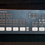Overhead shot of an ATEM Mini Pro video switcher on a dark surface, showcasing buttons and controls.