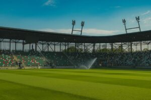 Panoramic view of an empty football stadium in Sosnowiec, Poland, under a clear blue sky.
