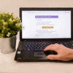 EvilTokens : le phishing dopé à l’IA ciblait les organisations Person using a laptop to read an email indoors beside a potted plant.