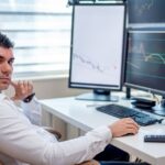 Cybersécurité : le stress devient un risque organisationnel Professional stock market analyst monitoring data on multiple screens at a workstation.