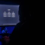 Agents IA hors contrôle : le problème est la gouvernance Silhouette of a person using ChatGPT on a computer screen in a dark room, highlighting digital interaction.
