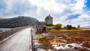 Scenic view of Eilean Donan Castle and bridge under cloudy sky in Scotland.