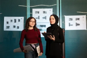 Two female architects reviewing blueprints in a modern office setting.