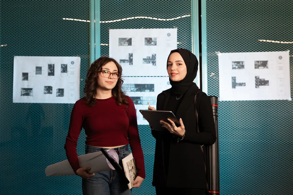 Two female architects reviewing blueprints in a modern office setting.
